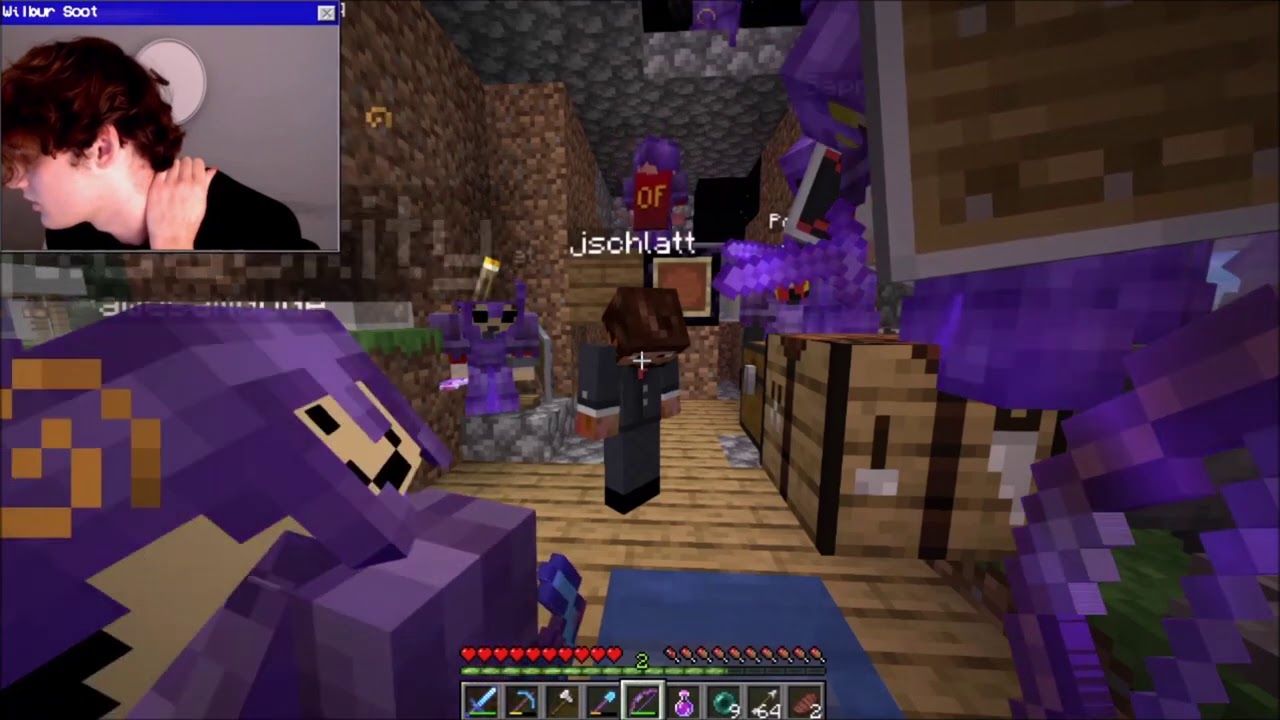 This is a screenshot from Wilbur's stream. He stands in the camaravan. It's been rebuilt out of wood, cobblestone, and dirt. Schlatt stands in the middle of the van. There is a crafting table to his right. Quackity is in the lower lefthand corner, looking up. Eret crouches behind Schlatt. Technoblade stands in the far back of the van. Other people wearing purple netherite armor can be seen, but it is unclear who they are or how many people are there in the screenshot. Wilbur's camera shows Wilbur turned away from his screen, rubbing the back of his neck.